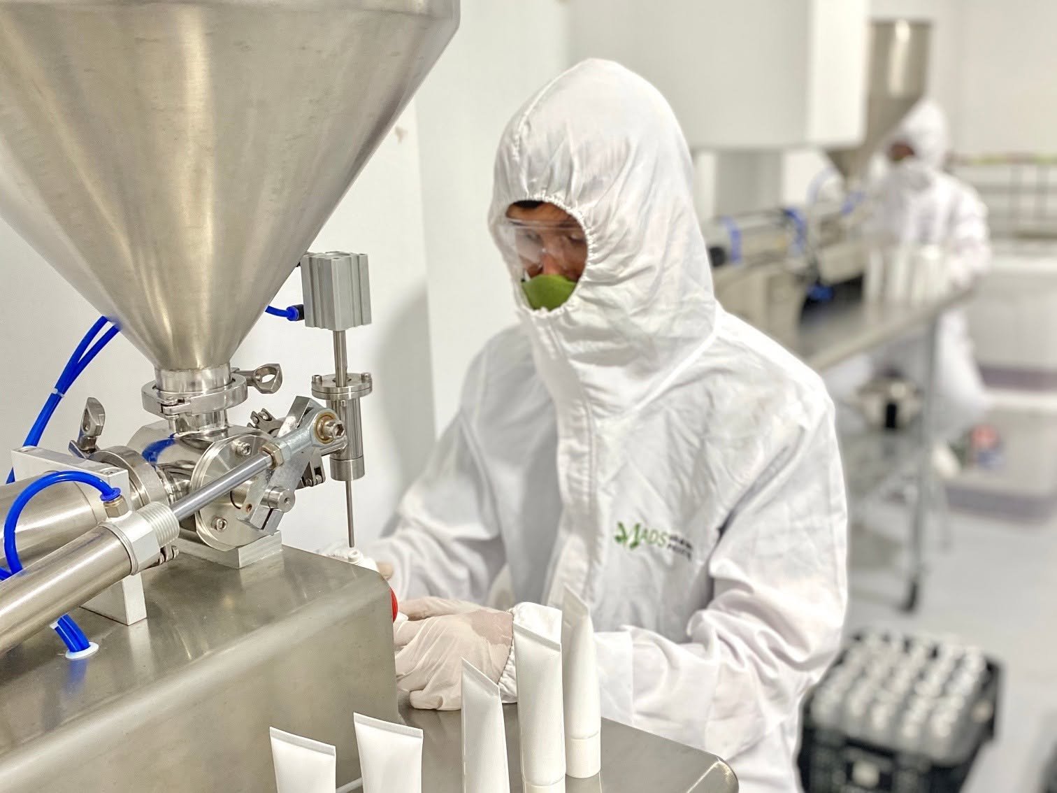 MADS production team in protective clothing filling product tubes with manufacturing equipment